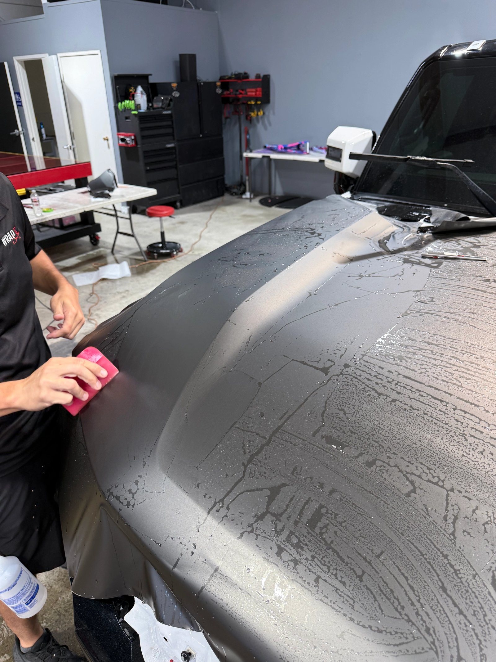 WrapFX installer applying vinyl film by hand to a vehicle hood
